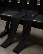 Black pants draped over a black bench in a locker room setting