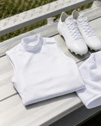White turtleneck shirt, white sneakers, and white towel on a wooden surface with a blurred natural background.