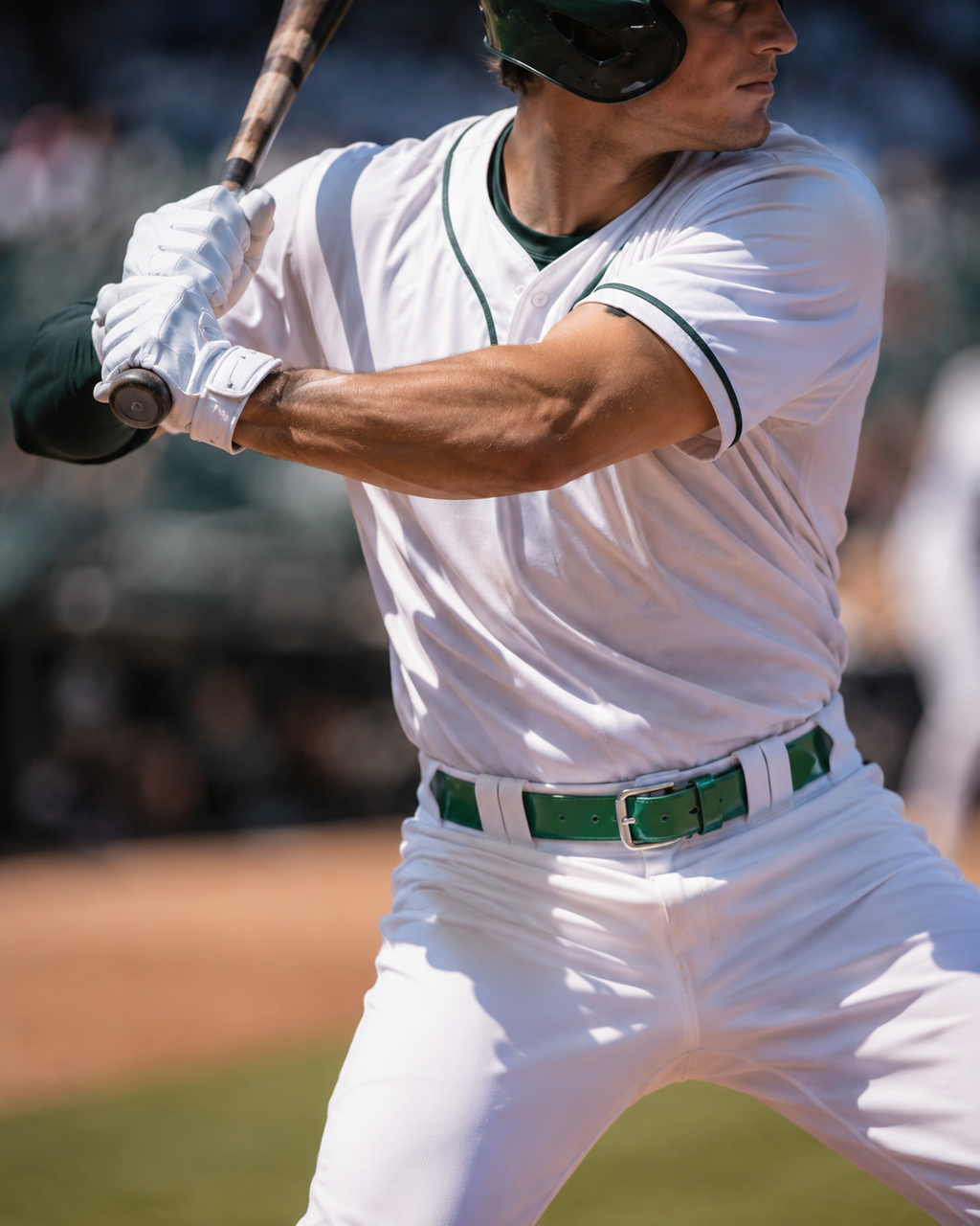 Baseball player in a white uniform with green accents, holding a bat on a baseball field.