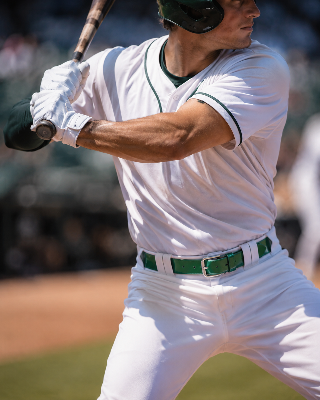 Baseball player in a white uniform with green accents, holding a bat on a baseball field.