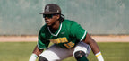 Baseball player in green uniform with sunglasses and protective gear on a field