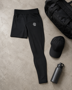 Black athletic pants with a logo, black cap, and black water bottle on a beige surface