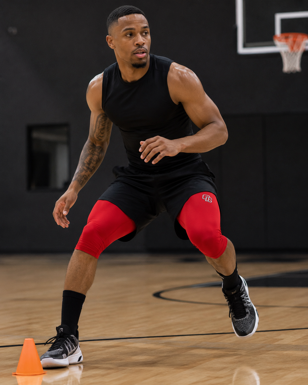 Person wearing black sleeveless shirt and shorts with red knee sleeves on a basketball court.
