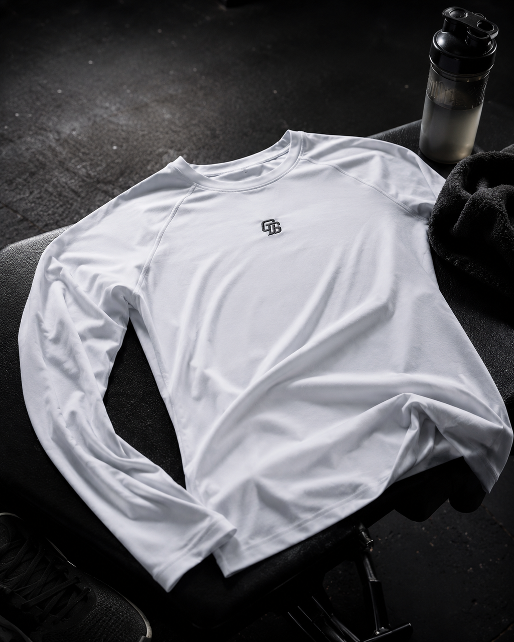White long-sleeve shirt with a logo on a dark surface