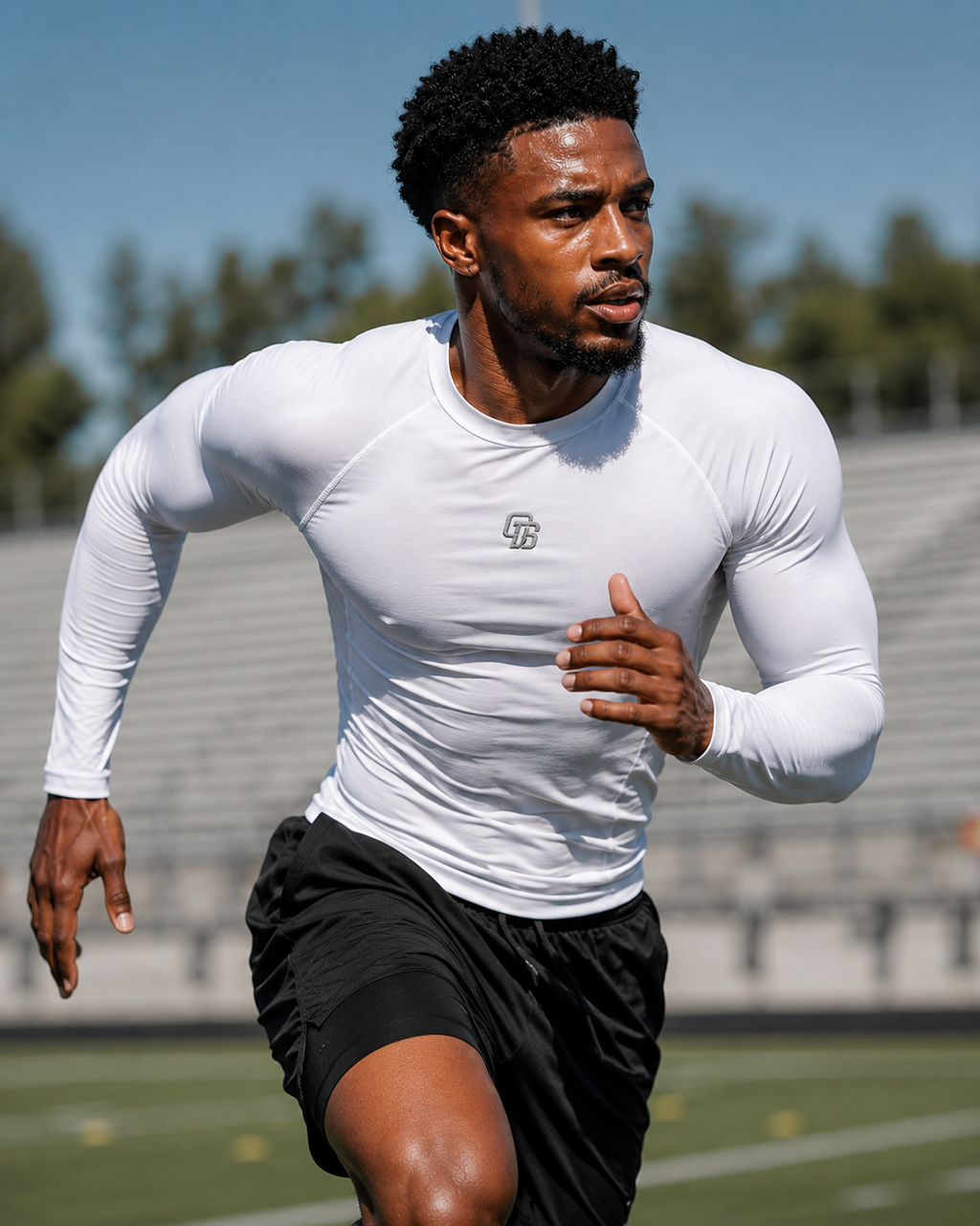 Man running on a track wearing a white long-sleeve athletic shirt and black shorts.